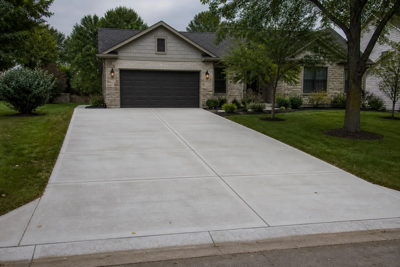 Finished concrete driveway leading to a suburban garage